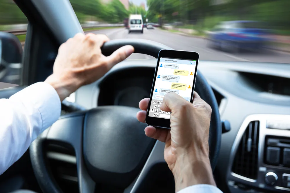 A man is using a phone while driving along the highway