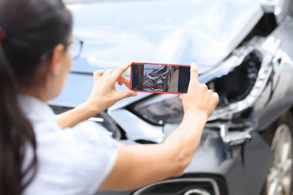 A woman is taking a photo of a car accident